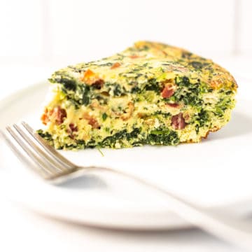 spinach and bacon quiche on a white plate