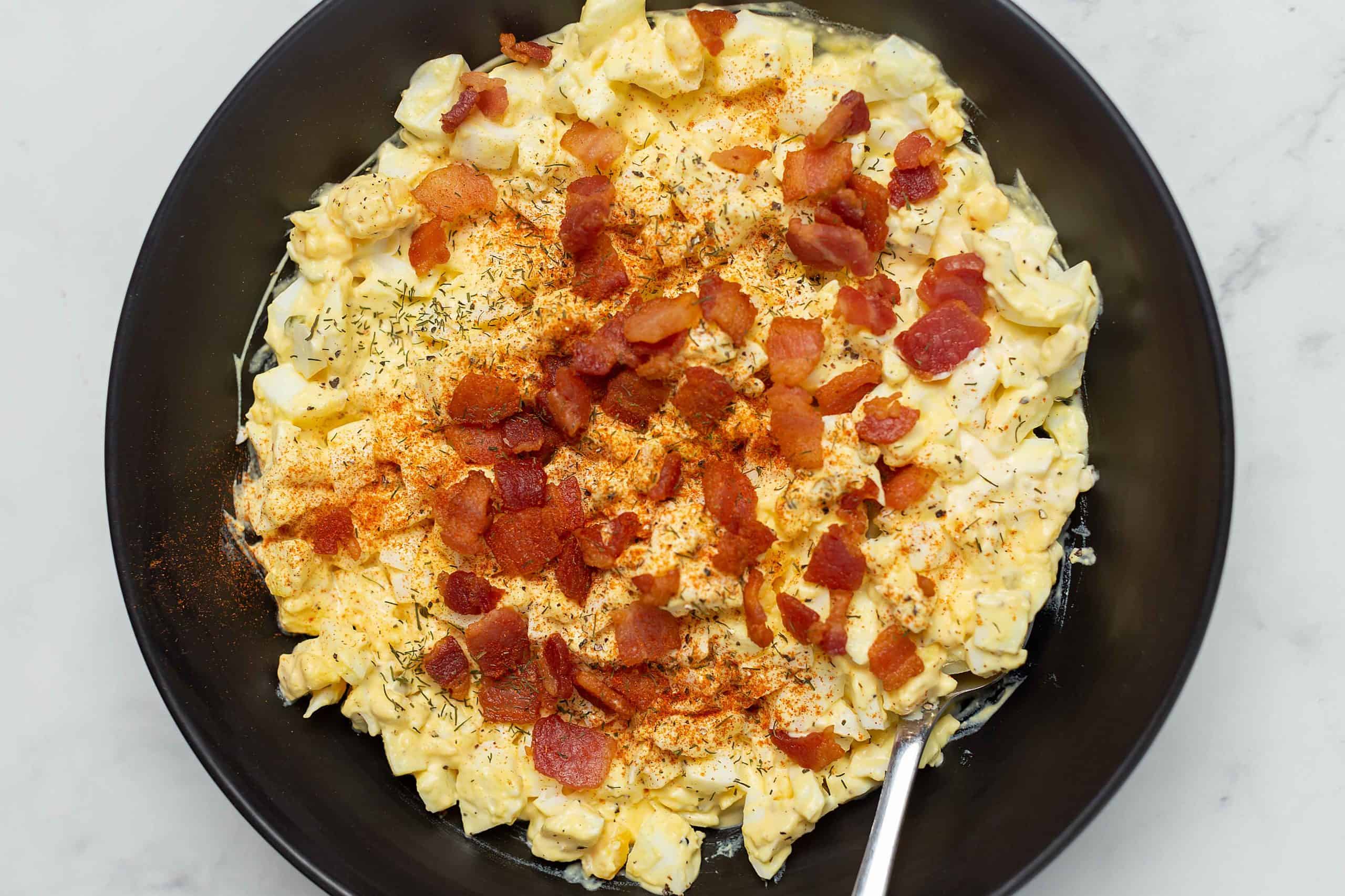 egg salad with bacon in a black bowl