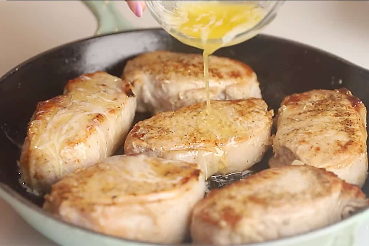pouring melted butter over pork chops