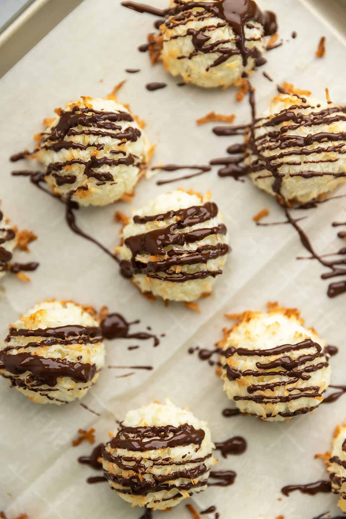 coconut macaroons drizzled with chocolate on a sheet tray