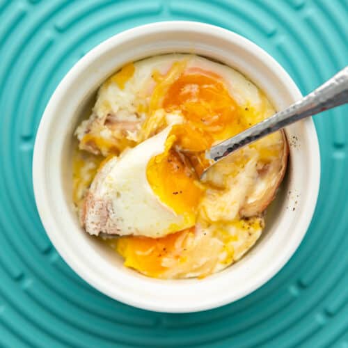 eggs baked in a ramekin on a teal background