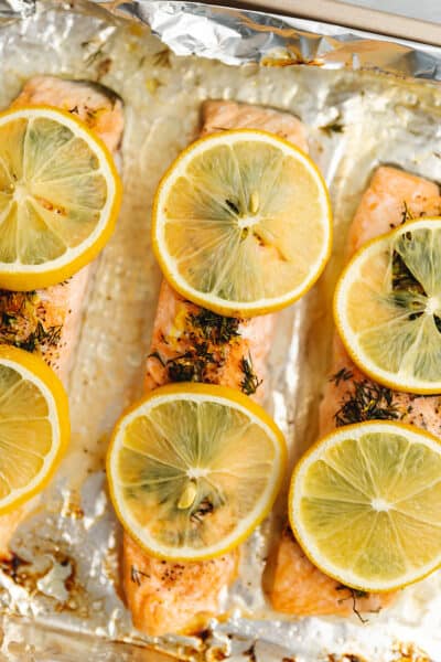 salmon topped with lemon slices on a sheet tray