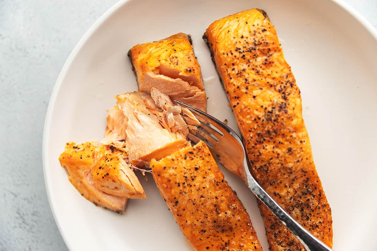 flaky frozen salmon in the air fryer on a white plate