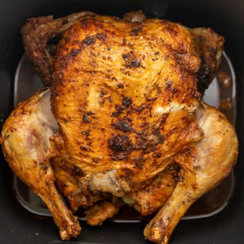 a whole chicken roasted in an air fryer basket