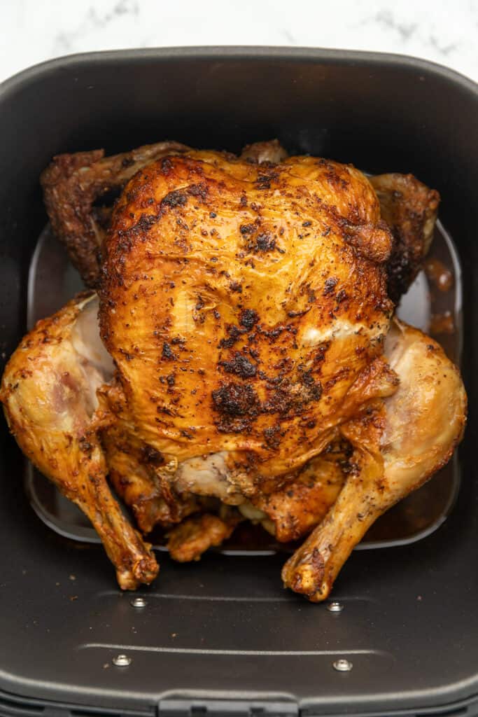 a whole chicken roasted in an air fryer basket