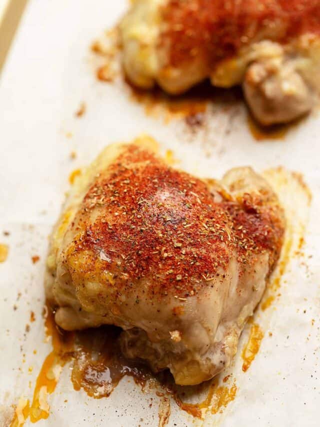 baked boneless chicken thighs with seasoning on a tray
