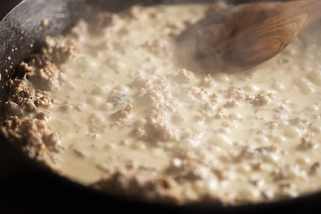 keto sausage gravy simmering in a cast iron skillet