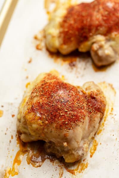 baked boneless chicken thighs with seasoning on a tray