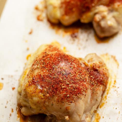 baked boneless chicken thighs with seasoning on a tray