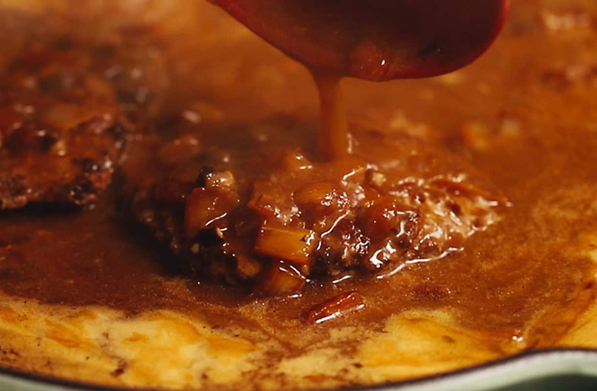 gravy being poured on cube steak