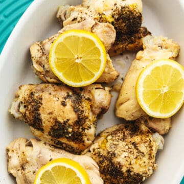 lemon slices over chicken thighs in a serving dish