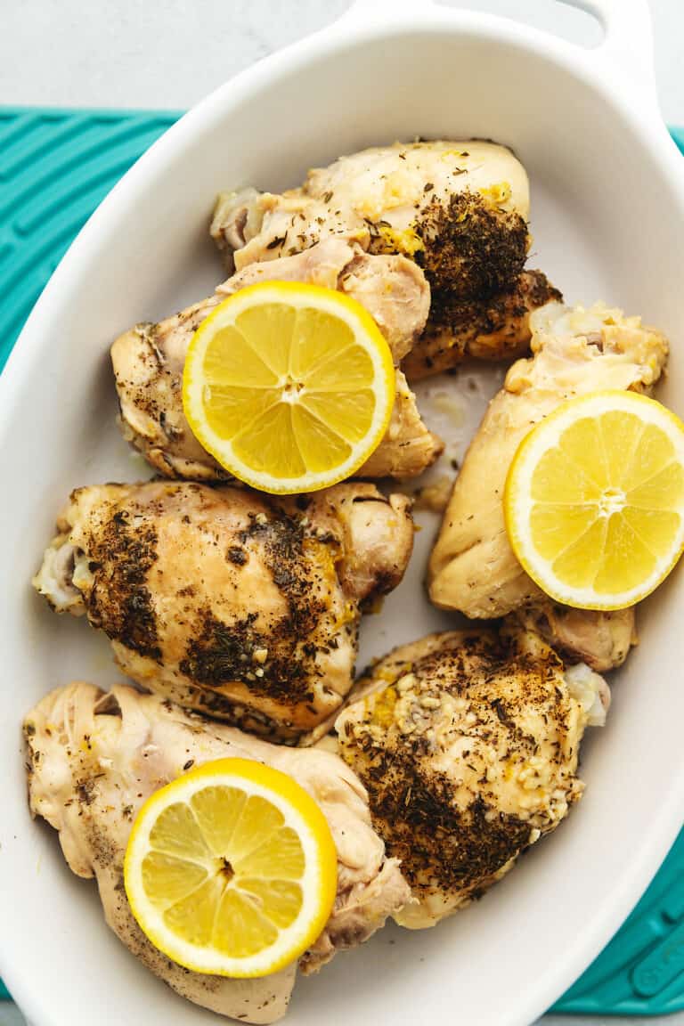 lemon slices over chicken thighs in a serving dish