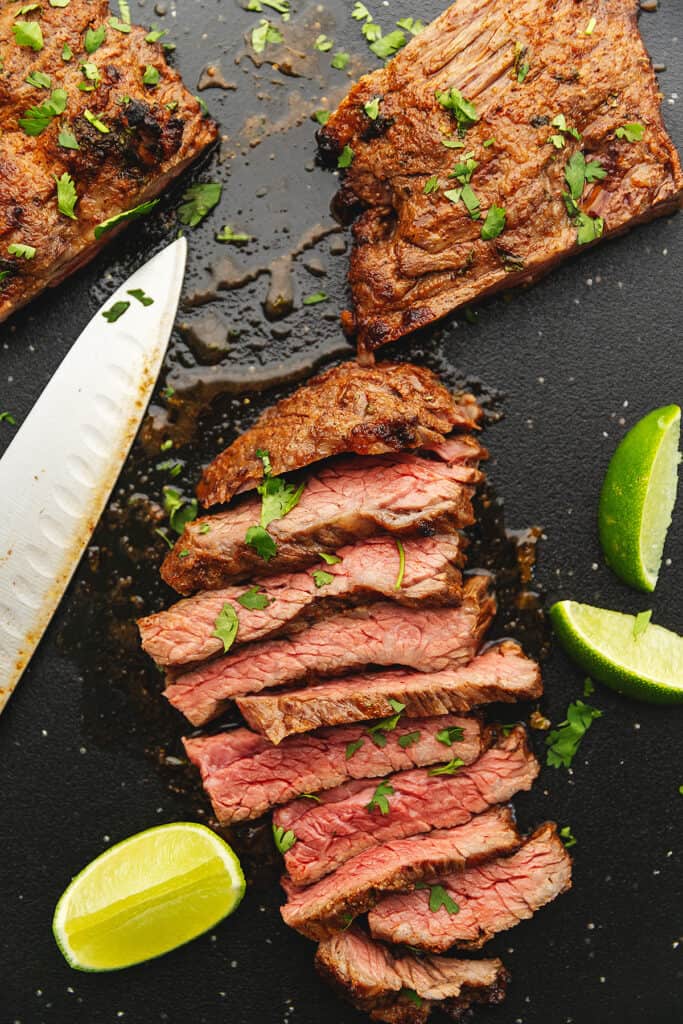 skirt steak on a cutting board with lime wedges