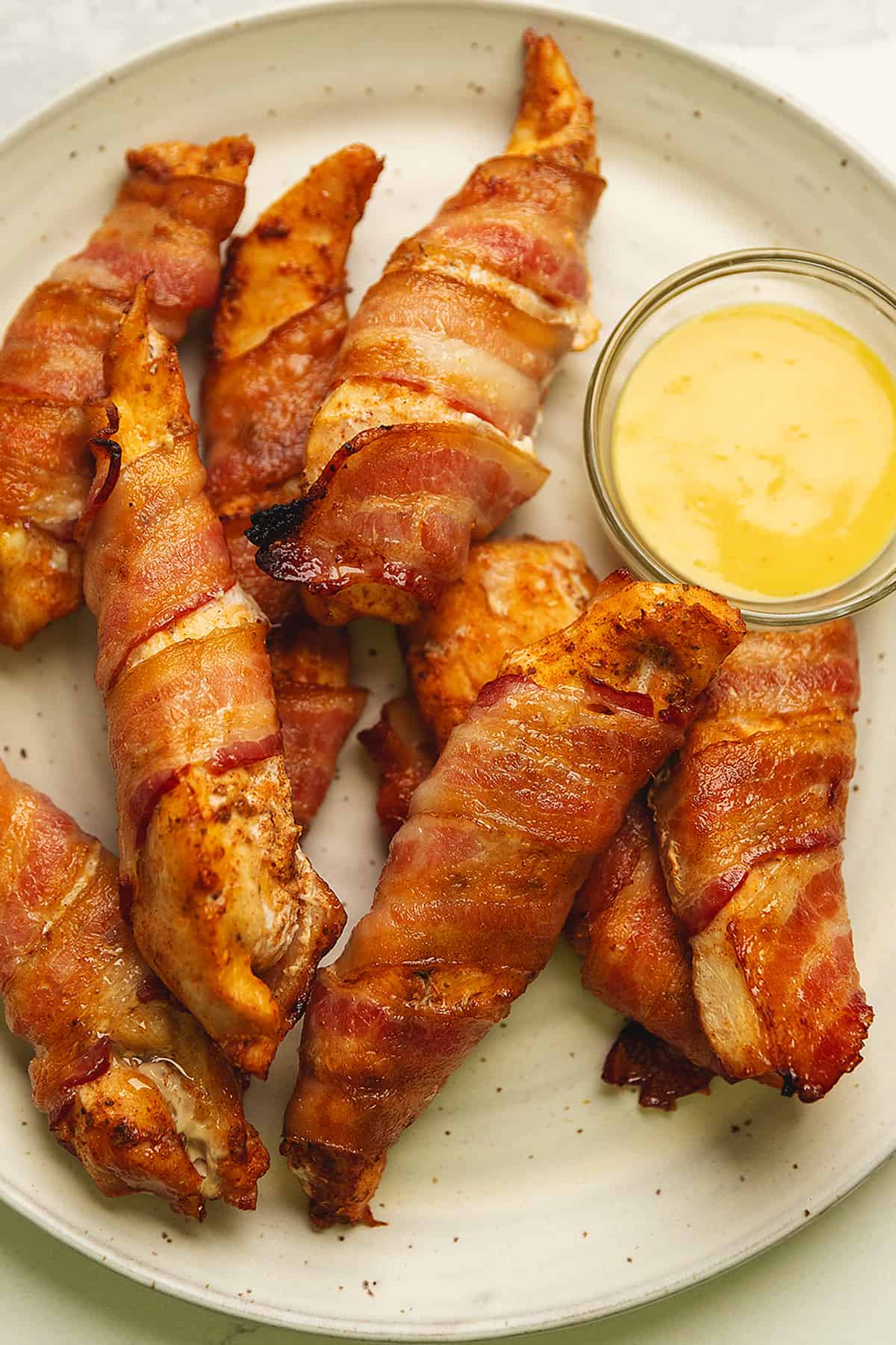 bacon wrapped chicken tenders on a plate with honey mustard