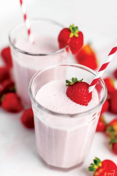 keto strawberry smoothie in a glass tumbler with whole strawberries as decoration