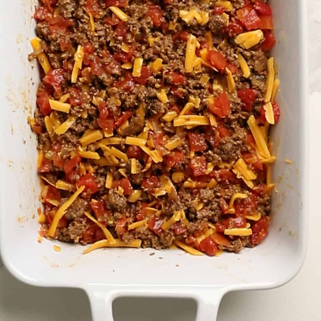 cheese, ground beef, and tomatoes in a casserole dish for a keto casserole