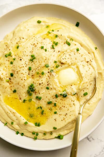 keto mashed potatoes with butter and chives in a white serving bowl