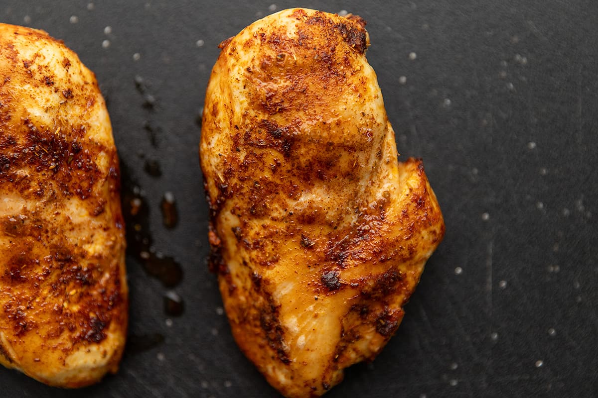 a chicken breast cooked perfectly on a black cutting board