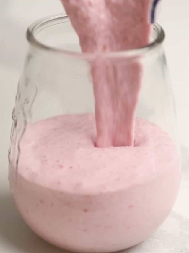a pink smoothie being poured into a glass