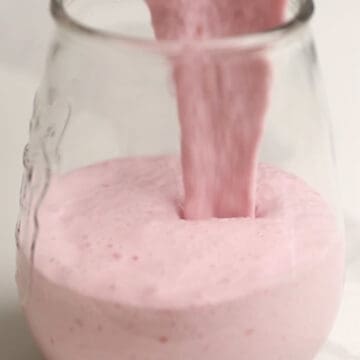 a pink smoothie being poured into a glass