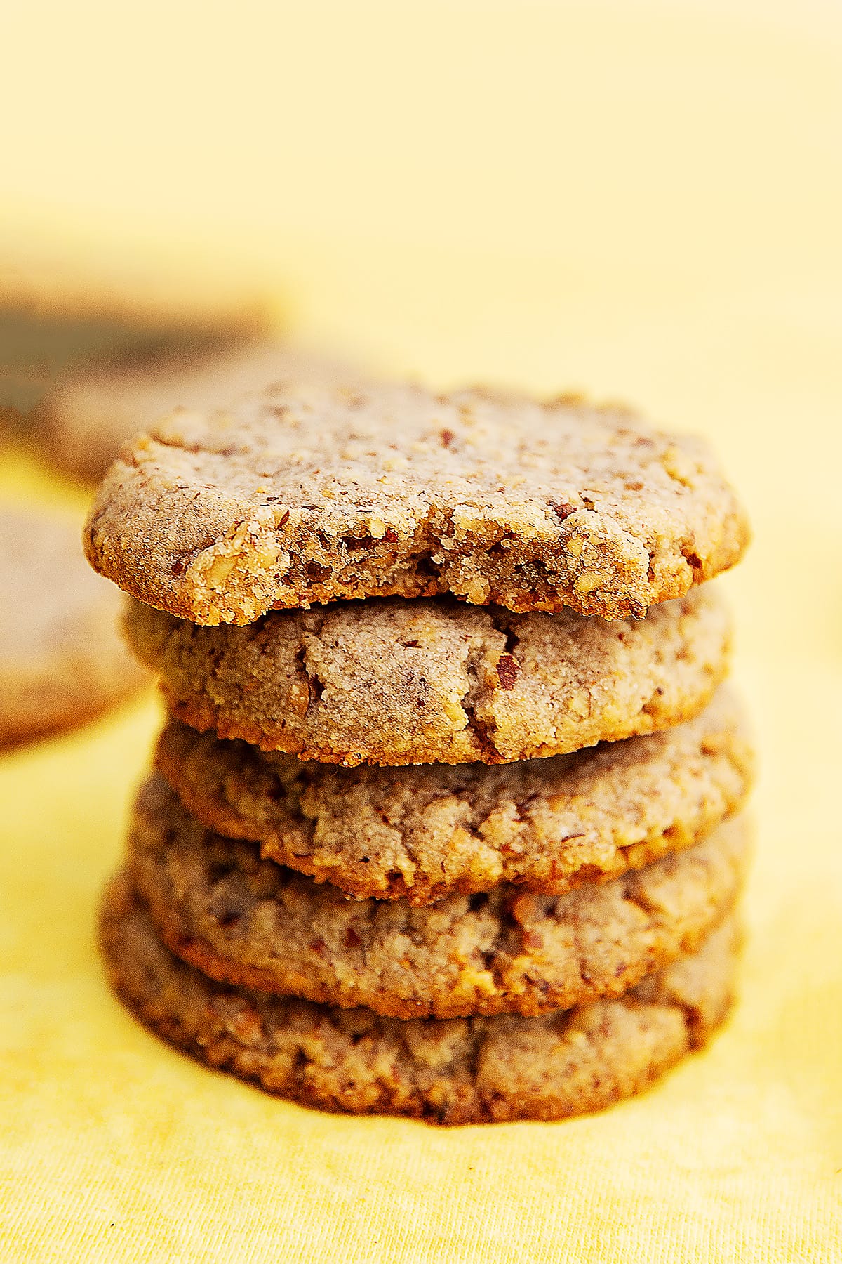 a stack of 4 pecan cookies on a yellow background