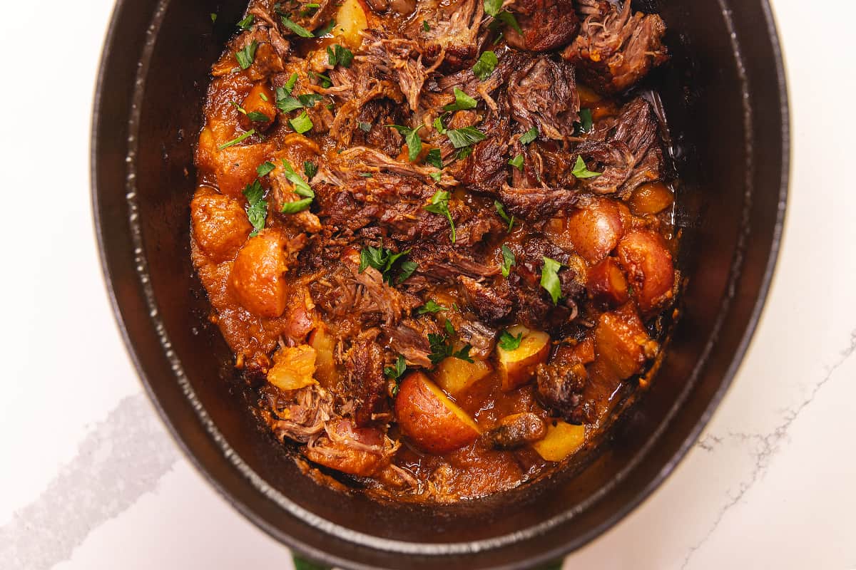 a staub dutch oven with roast and potatoes
