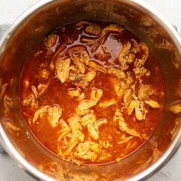 a pot with shredded chicken in a red sauce