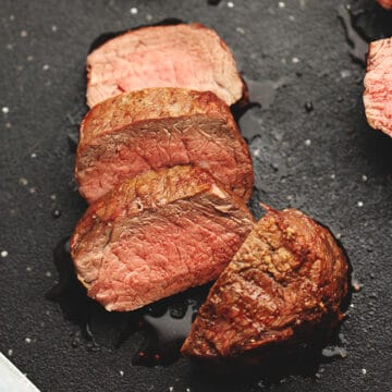 filet mignon cooked in the air fryer sliced on a black cutting board