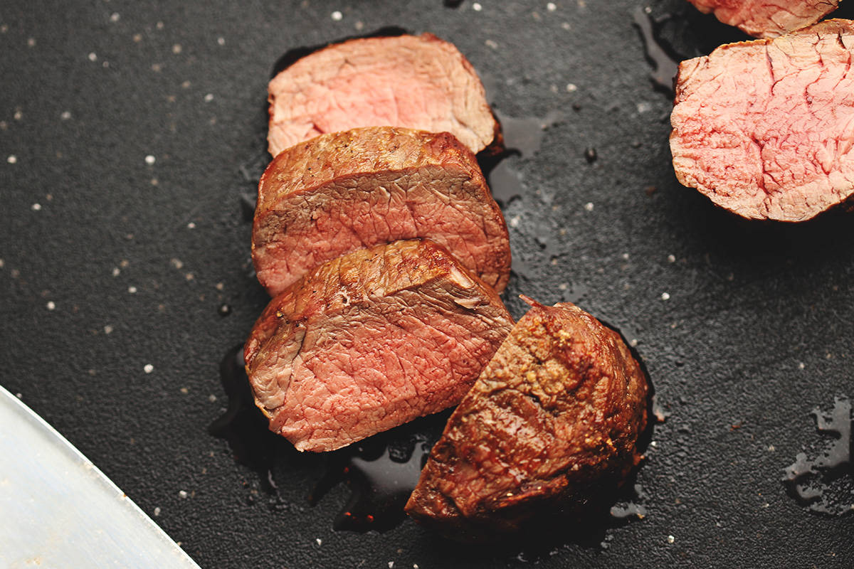 filet mignon cooked in the air fryer sliced on a black cutting board