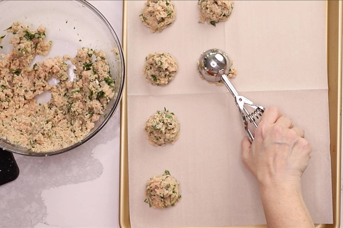 scooping meatballs into a sheet pan