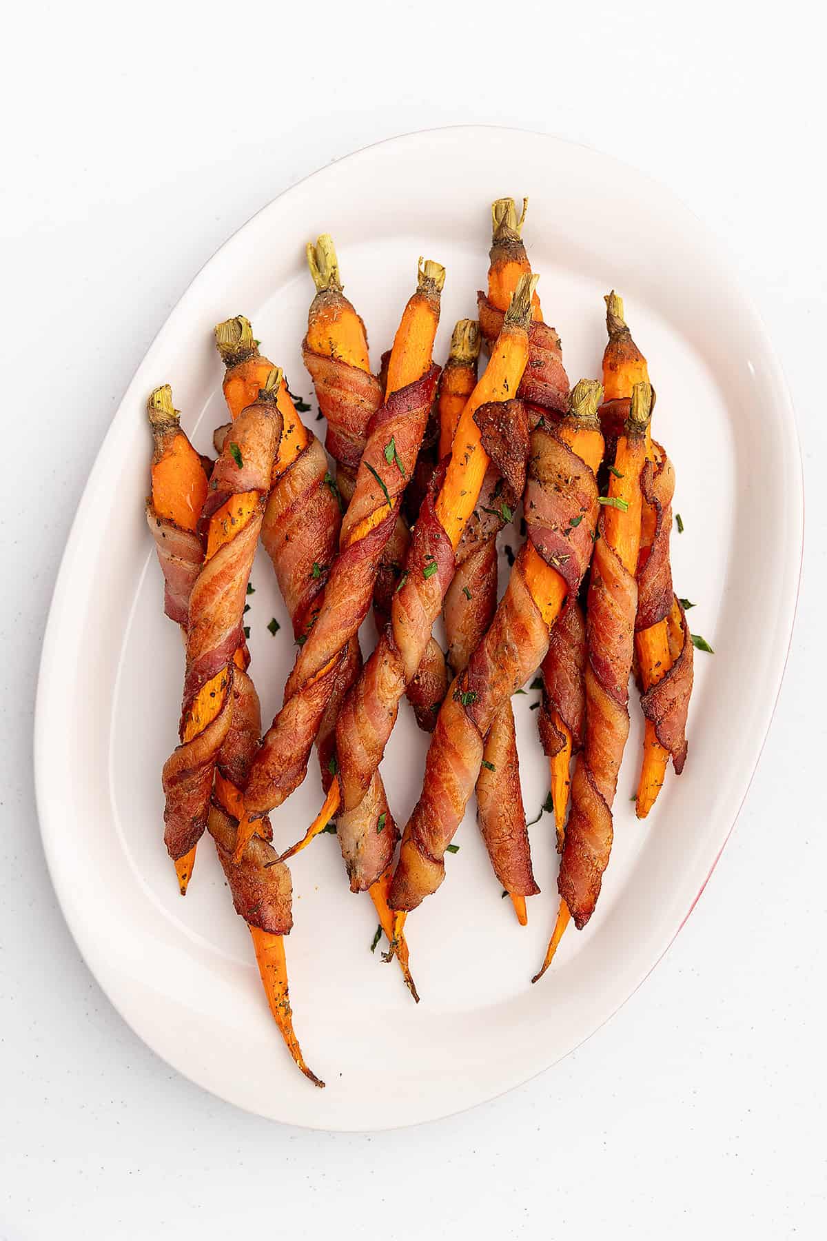 bacon wrapped carrots on a white serving platter
