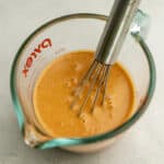 a creamy orange sauce in a pyrex measuring cup