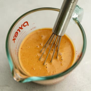 a creamy orange sauce in a pyrex measuring cup