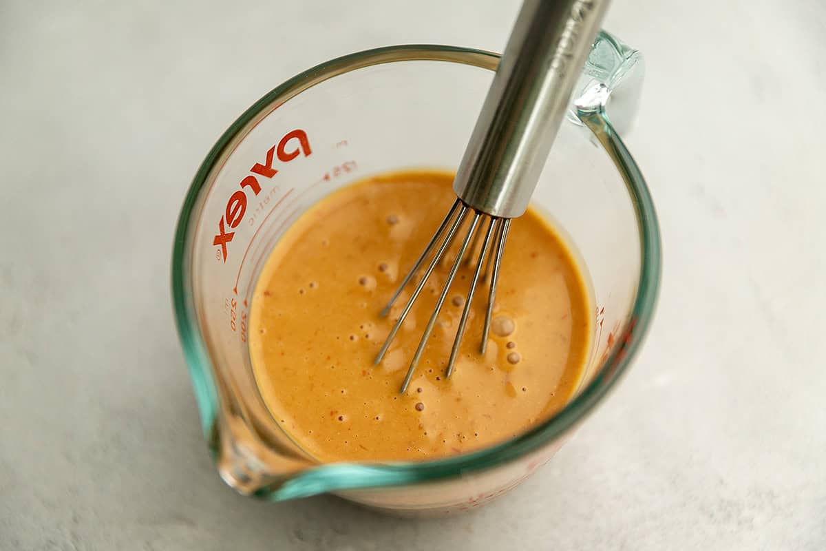 a creamy orange sauce in a pyrex measuring cup