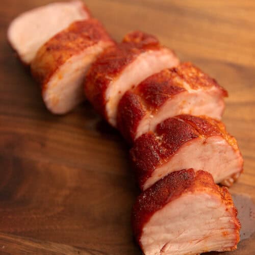 smoked pork tenderloin sliced on a wooden cutting board