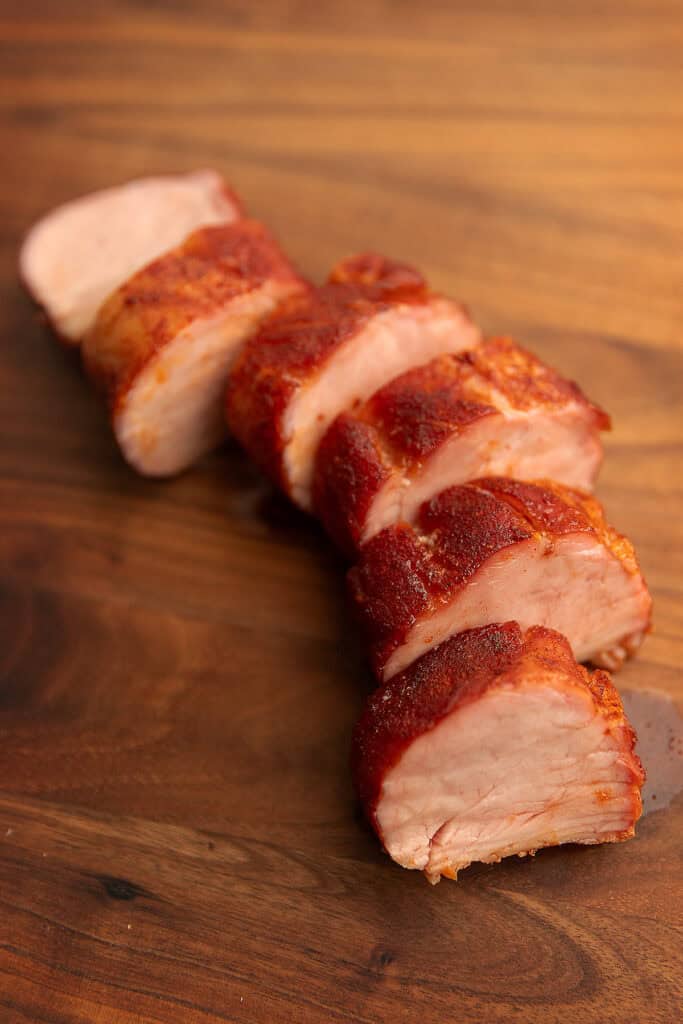 smoked pork tenderloin sliced on a wooden cutting board