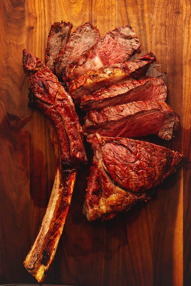 a cut tomahawk steak on a wooden cutting board