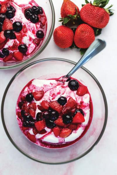 sweetened berries over yogurt in a glass bowl