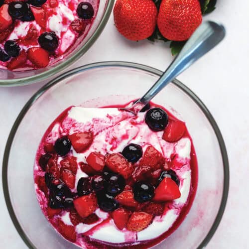 sweetened berries over yogurt in a glass bowl