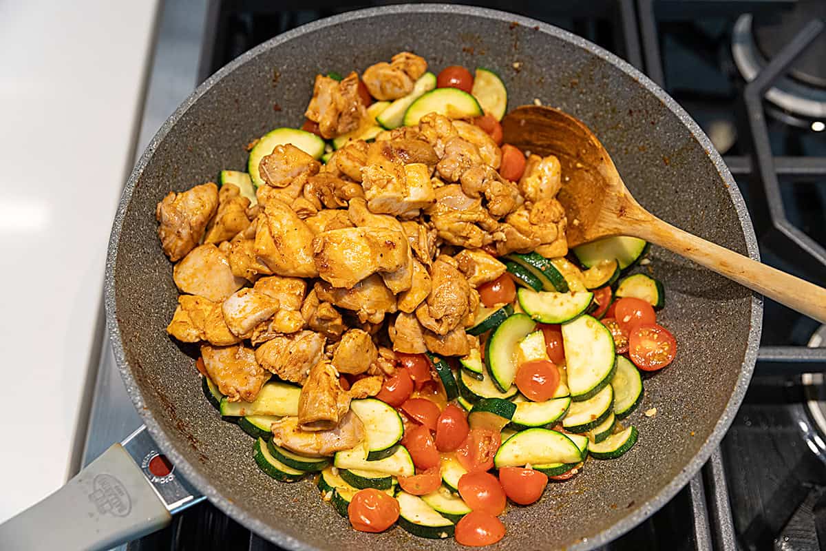 chicken, zucchini and tomatoes cooking in a skillet