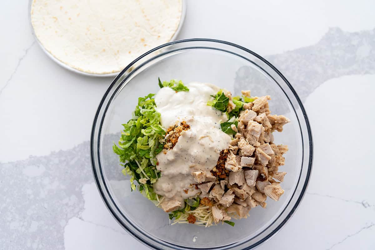 chicken caesar salad ingredients in a bowl