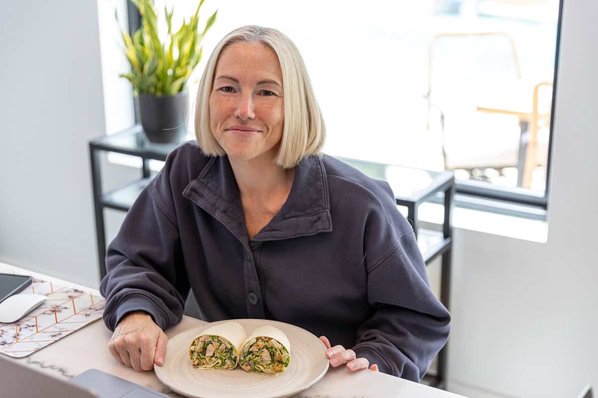 Jennifer Banz eating a chicken caesar wrap at her laptop
