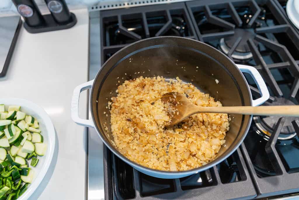 sautéed onions and cauliflower rice in a pot on the stove top.