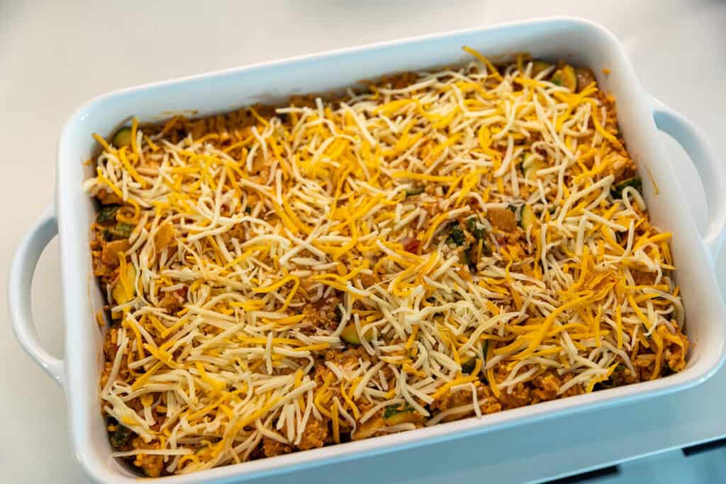Overhead view of chicken taco casserole topped with Mexican-blend cheese before baking