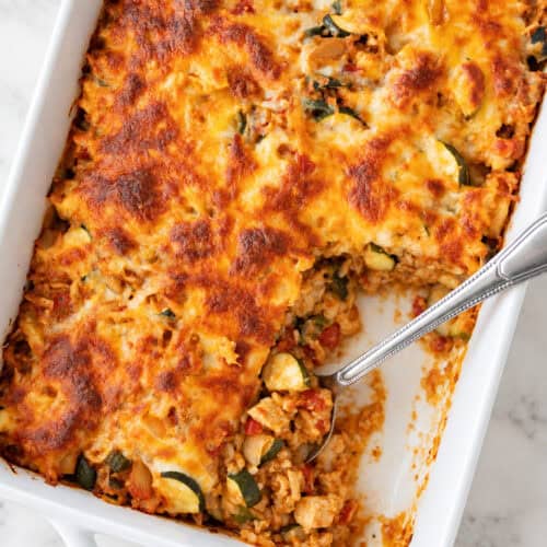 High protein chicken taco casserole with golden melted cheese in a white baking dish.