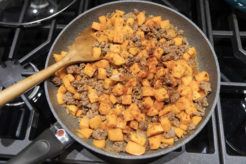sweet potato, ground beef, and onions cooking in a skillet