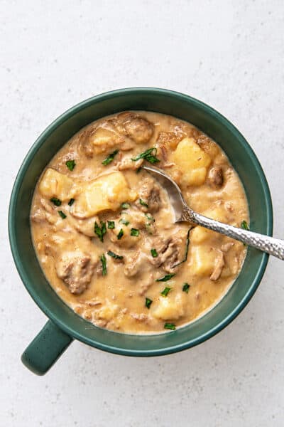 a green bowl filled with slow cooker creamy beef stew