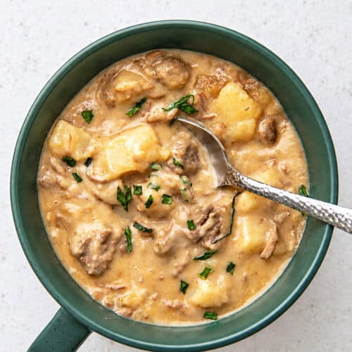 a green bowl filled with slow cooker creamy beef stew