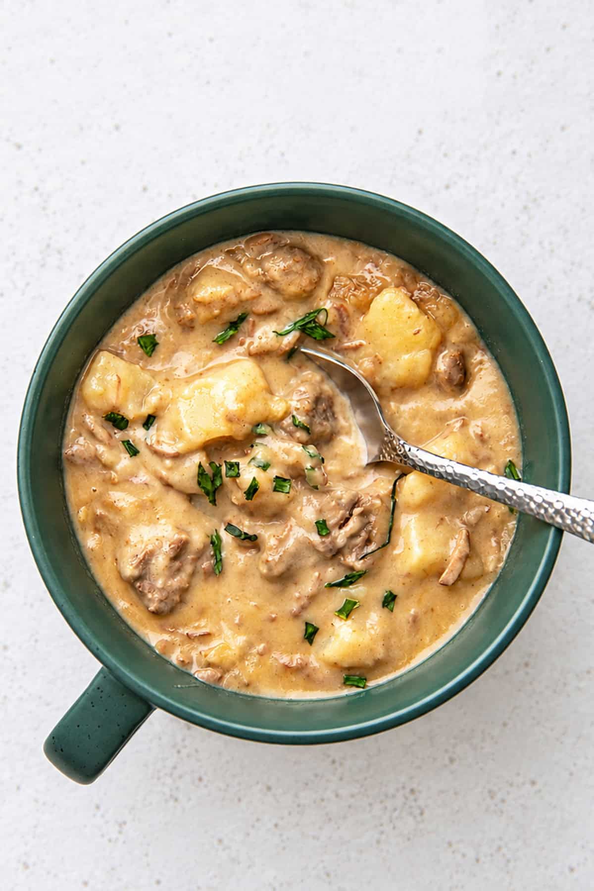 a green bowl filled with slow cooker creamy beef stew